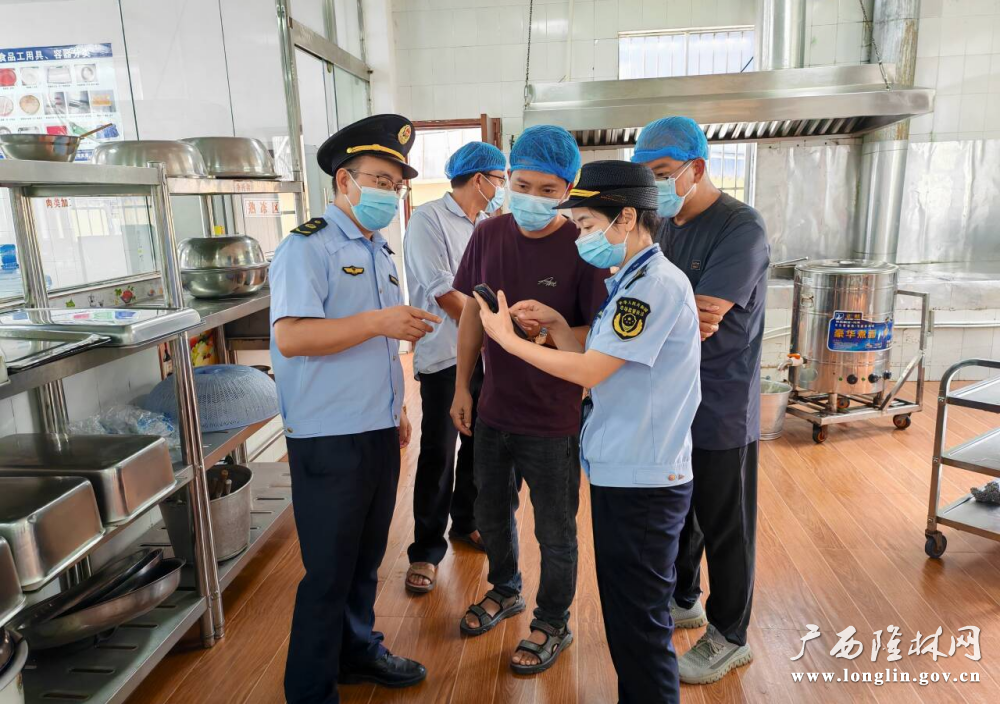 图为执法人员利用手机开展学校食堂食品安全员“广西食安”APP食品安全知识培训现场